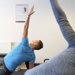 Personal Trainer von BodyConcept Berlin zeigt eine Mobilitätsübung im Trainingsraum